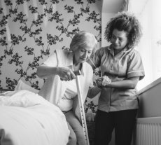 caregiver helping elder woman in standing up