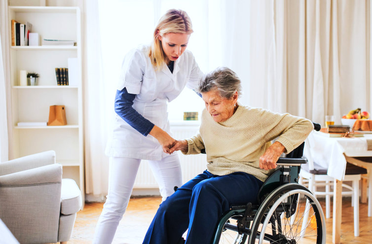 elderly woman in a wheelchair assisted by caregiver in standing up