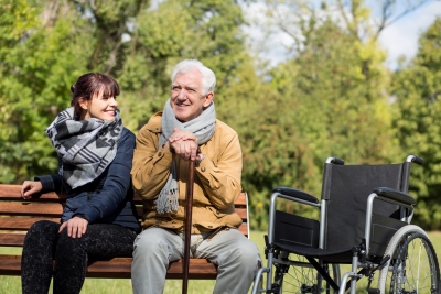 elder man with caregiver sitting on a bench outdoors