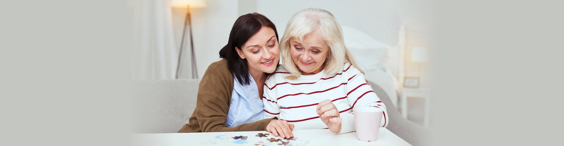 caregiver helping elder woman in solving a puzzle