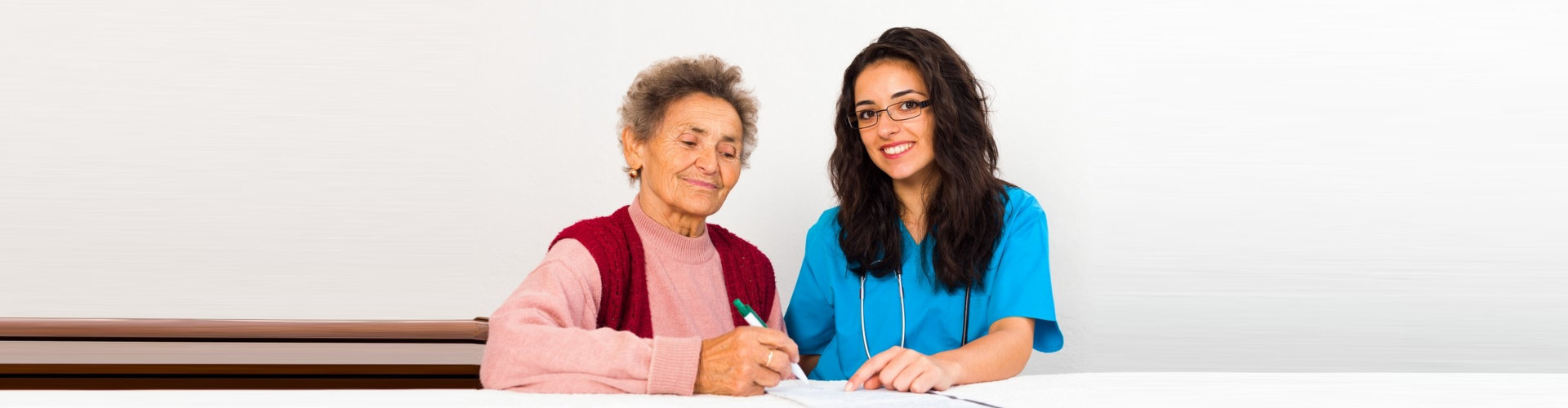 caregiver helping elder woman in filling up forms